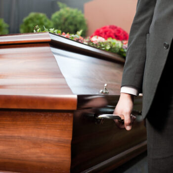 Religion, death and dolor  - coffin bearer carrying casket at funeral to cemetery