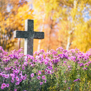 Concrete cross in cemetery in autumn